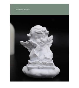 Detail of white resin angel sculpture reading a book on a cloud base with matte texture