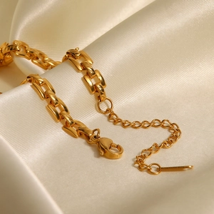 Détail d'une chaîne en acier doré 18K avec fermoir mousqueton sur soie beige