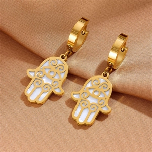Detail of golden Hamsa Hand earrings with white shell inlay on champagne satin background
