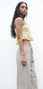Détail du haut bandeau beige avec broderie élégante et bordure à volants