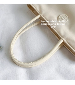 Vue détaillée des poignées rondes renforcées sur un sac seau en nylon crème chic