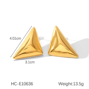Macro detail of high-polished golden triangular stud earrings with 3D geometric design