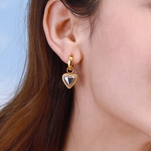 Two-tone 18k gold plated stainless steel heart hoop earrings worn by a model
