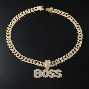 Macro detail of gold Cuban link chain with sparkling iced-out BOSS letter pendant