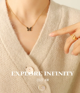 Close-up of bohemian gold butterfly pendant necklace and matching ring on model