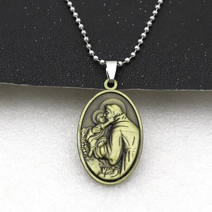 Detail of vintage bronze oval pendant featuring a religious relief carving on a silver ball chain
