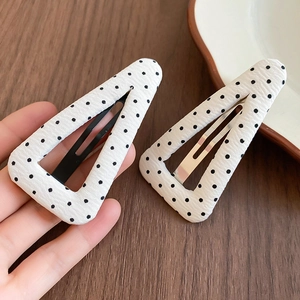 Dettaglio delle mollette in tessuto a pois neri su bianco con chiusura in metallo