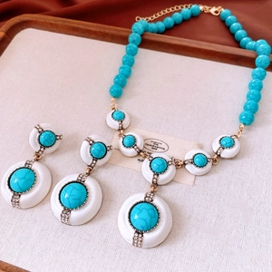 Vue détaillée d'une parure vintage avec turquoise, émail blanc et strass scintillants