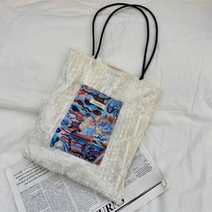 Detail of cream lace tote bag featuring abstract oil painting pocket and thin black handles