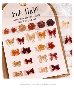 Macro detail of Maillard resin nail charms featuring amber camellias and vintage bows