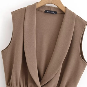 Detail of brown crinkle fabric sleeveless top with cross V-neck on wooden hanger
