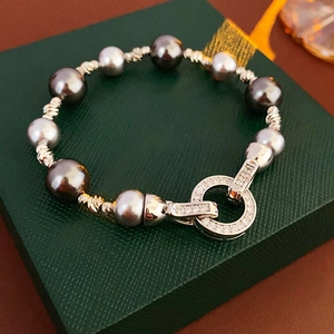 Macro detail of dark and silver grey pearl bracelet with textured beads on a green box