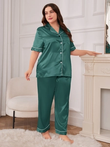 Deep green satin pajama set featuring white piping detail and short sleeves in a chic room