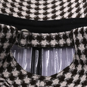 Close-up of adjustable metal buckle and houndstooth fabric texture on baseball cap