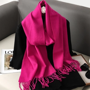 Detail of rose red cashmere scarf with fringe tassels on black stylish outfit