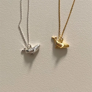 Detailed view of creative whale pendant necklaces in polished silver and gold finishes