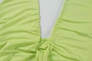 Detail of bright green knit dress featuring ruched v-neckline and fine stitching