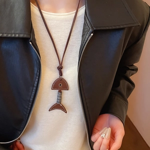 Close-up of retro fishbone pendant necklace with brown leather and metal on a model