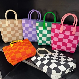 Knitted checkerboard tote bags in multiple colors displayed on a modern black shelf