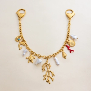 Detailed view of gold ocean charms featuring pearls, sea turtles, and red coral pendants