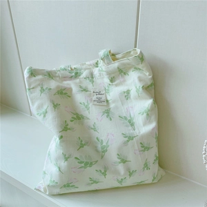 Detail of floral canvas tote bag with green leaves and pink rosebuds on off-white fabric