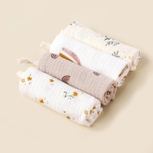 Detail von vier Musselin-Babyhandtüchern mit Aufhängeschlaufen und Blumenmustern