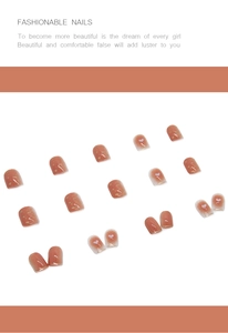 Close-up of warm peach gradient press-on nails with white heart patterns and gold flakes