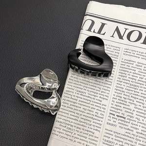 Close-up of irregular metallic hair claw clips in silver and matte black on a magazine
