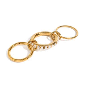 Three interconnected gold bands with central pearl circle on a minimalist background