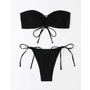 Flat lay of black bandeau bikini set with textured seersucker fabric and side-tie bottoms