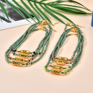 Detail of beaded turquoise necklace featuring a gold-plated evil eye pendant and clasp