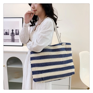 Blue and white striped woven tote bag with rope handles shown on model for size and capacity