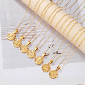 Close-up of gold round alphabet pendants with radiating texture and engraved letters