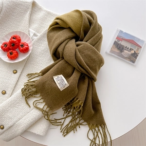 Detail of soft brown and olive green gradient cashmere-like scarf with fringe and label
