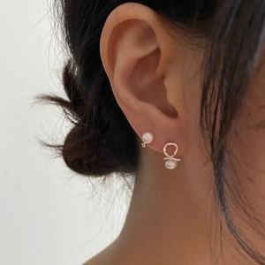 Detailed view of sterling silver freshwater pearl earrings with a knot design worn by a model