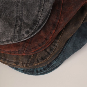 Close-up of vintage distressed berets showing faux leather texture and stitching detail
