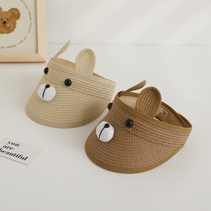 Close-up of children straw sun visors with 3D cartoon bear faces in beige and brown