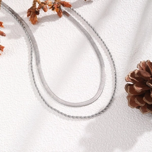 Detailed view of silver double-layered snake and twisted chain necklace with decor