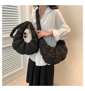Detail of a black pleated dumpling bag set featuring a crossbody and handbag with soft texture