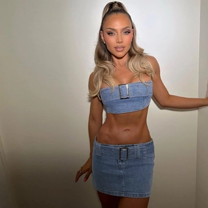Detail of blue denim two-piece set featuring large metal buckle on tube top and mini skirt