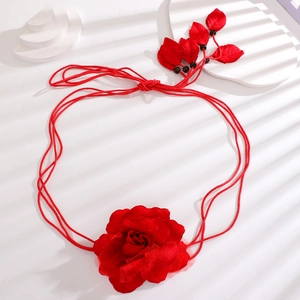 Close-up of red chiffon flower belt with woven rope and leaf detail on white background
