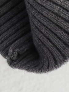 Close-up of dark grey ribbed knit texture and premium stitching on a bomber jacket
