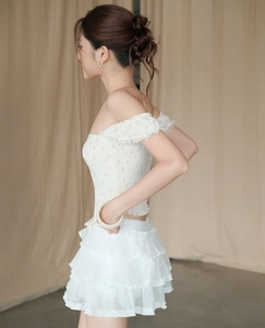 Detail van de witte gebloemde off-shoulder top en gelaagde rok met ruches