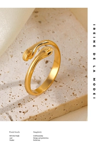 Macro shot of gold-plated wrap ring with hand-holding design on a satin backdrop