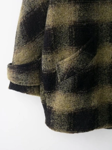 Macro shot of green and black plaid wool blend fabric showing texture and stitching
