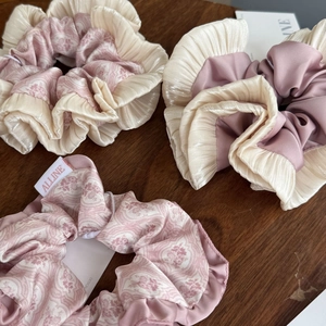Detail of floral and solid pink scrunchies with cream frill trim on dark wood