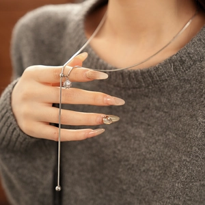 Detail of silver snake chain necklace with adjustable ball pendant and crown charm