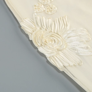 Detailed macro view of ivory ribbon flower embroidery on delicate mesh fabric