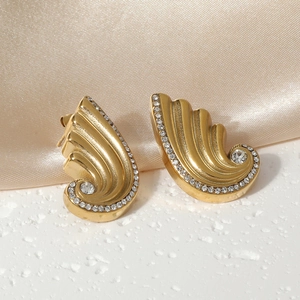 Detailed close-up of 18K gold plated wing earrings with sparkling crystals on silk background