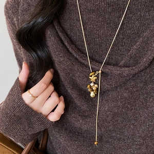 Nahaufnahme der Vintage Goldkette mit Stern- und Perlenanhänger auf braunem Pullover